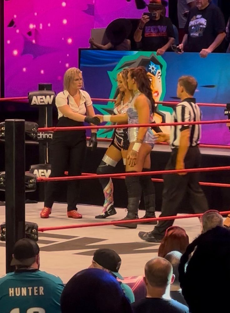A picture of Toni Storm, Harley Cameron and Kris Statlander in the ring. Toni is shaking Kris’ hand.