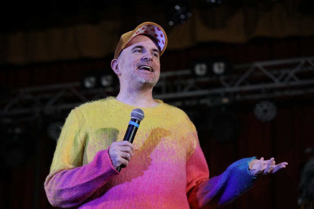 Me, asking some sort of question with my palm face up, in a shot where the lighting rig is somewhat visible behind me