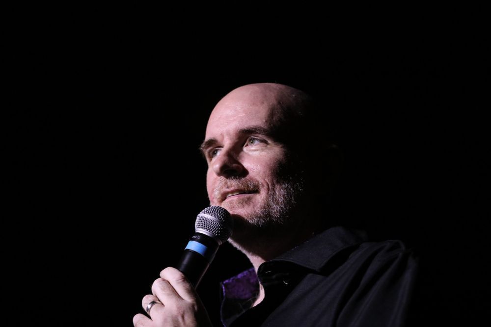 A closeup shot of me grinning into a microphone being very bald