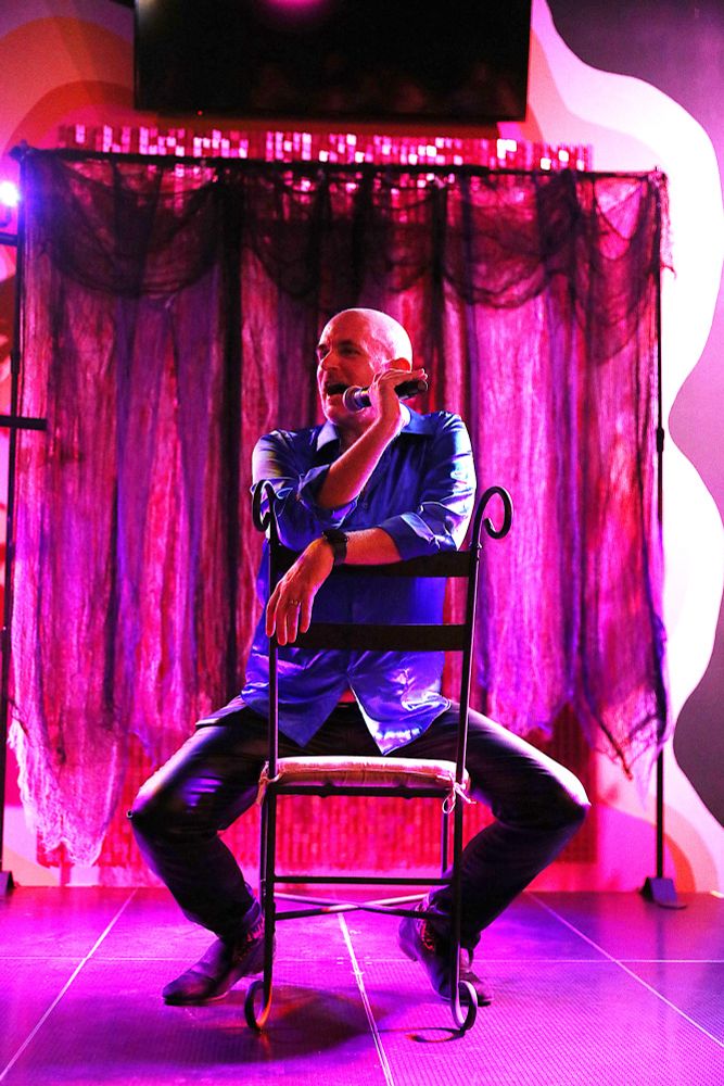 Me, sitting on a chair on a very pink stage, welcoming the audience