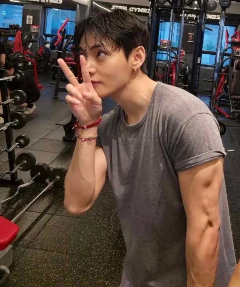 buff taehyung making a peace sign, looking to the side and half covering his face. 