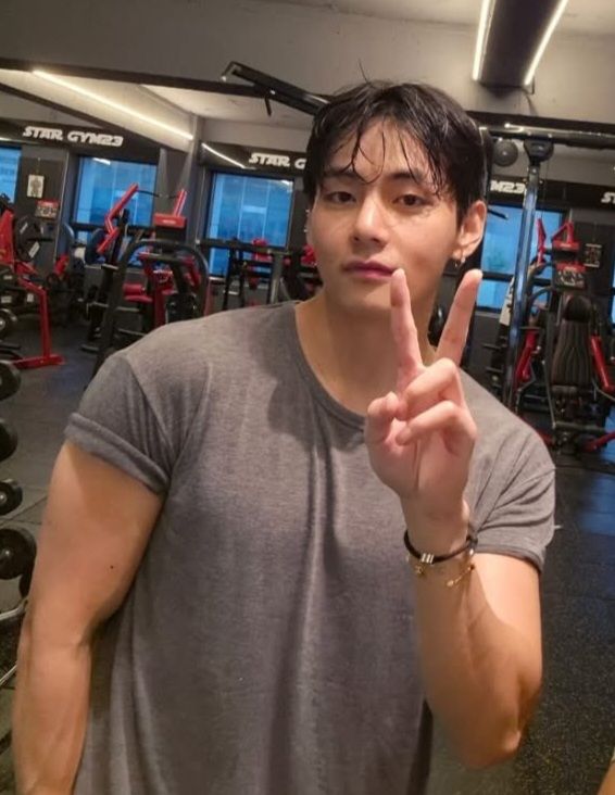 buff taehyung making a peace sign, facing the camera. he looks so big... his arms...