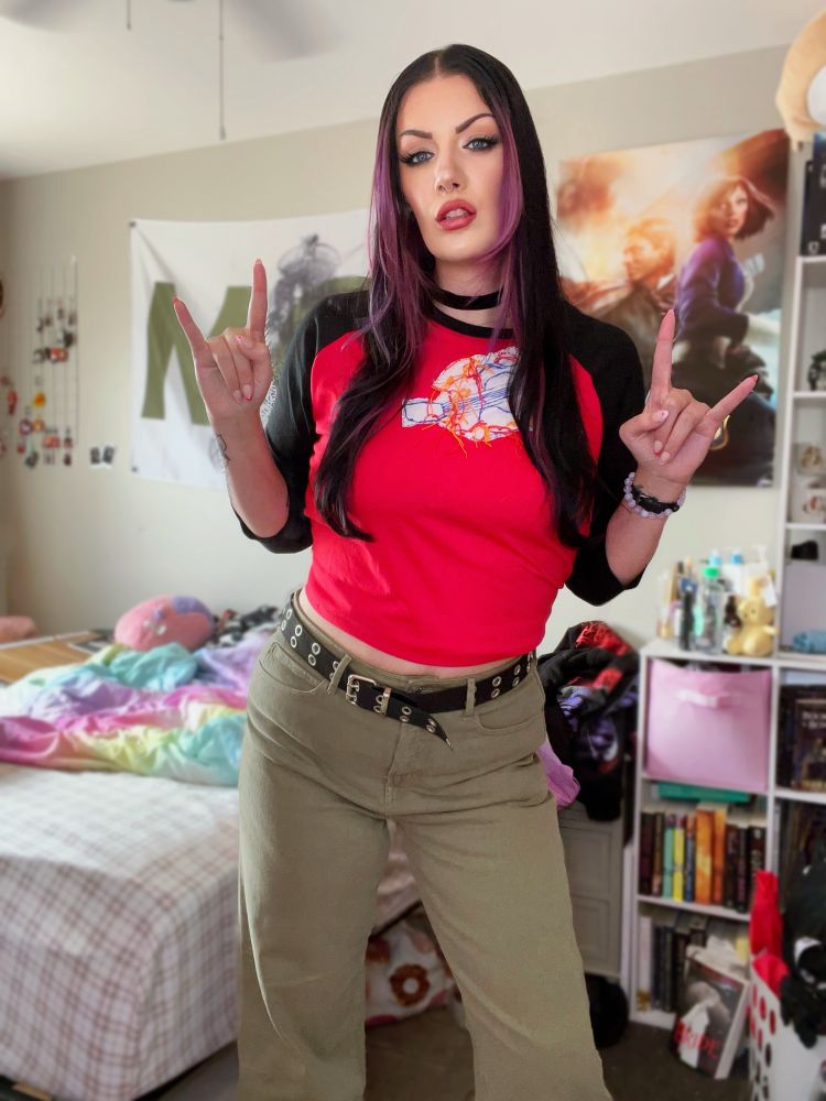 Villanarei cosplaying Anna from Freaky Friday, standing in her room, making rock on symbols with her hands.