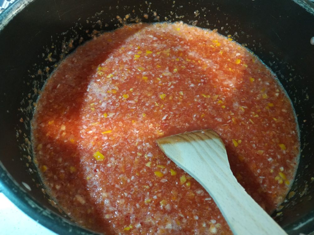 Una pentola nera con della marmellata di arance