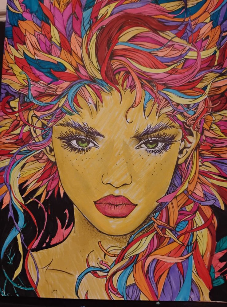 A coloring book page of a woman staring straight at the camera. Her eyes are piercing green. Her hair is wild and flowing out from her head in a combination of feathers and flames, shades of red, orange, yellow, purple, and blue interspersed within. 