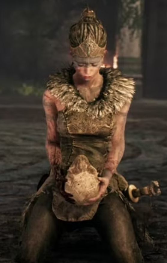 Senua from Hellblade: Senua's Sacrifice. Senua is a Pict warrior with dreadlocked hair pulled into a ponytail. She has a leather headpiece and clothing with fur collar. She holds the skull of her beloved, Dillion.