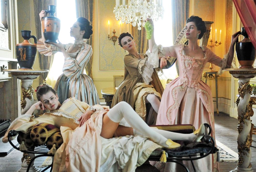 A group of rather wanton young ladies pose in an 18th century drawing room