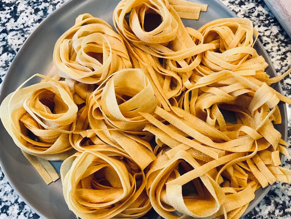 A large plate full of bundles of fresh golden fettuccine waiting to go in the pot.