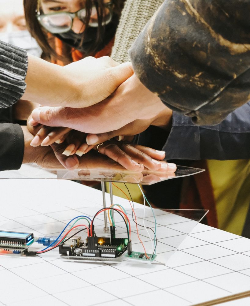 Photo of a microcontroller connected to an LED screen and an acrylic sheet with people's hands on top of it