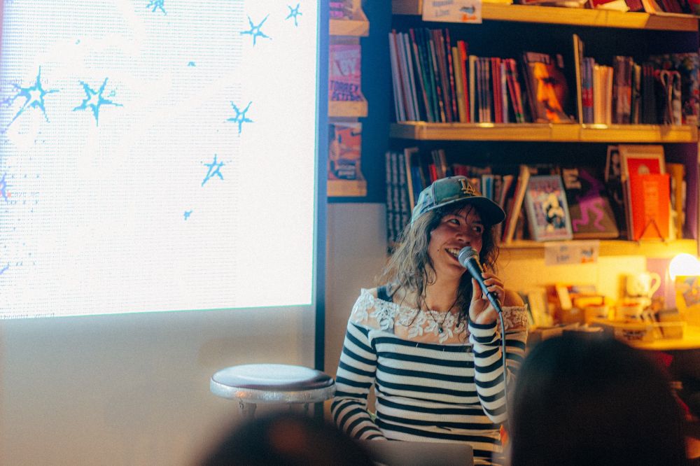 An attendee holds a microphone, behind her there’s dithered stars projected.