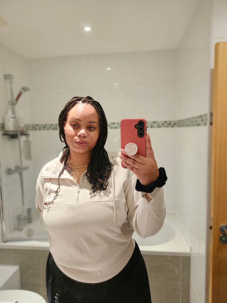 A woman looking into a bathroom mirror, holding her phone 