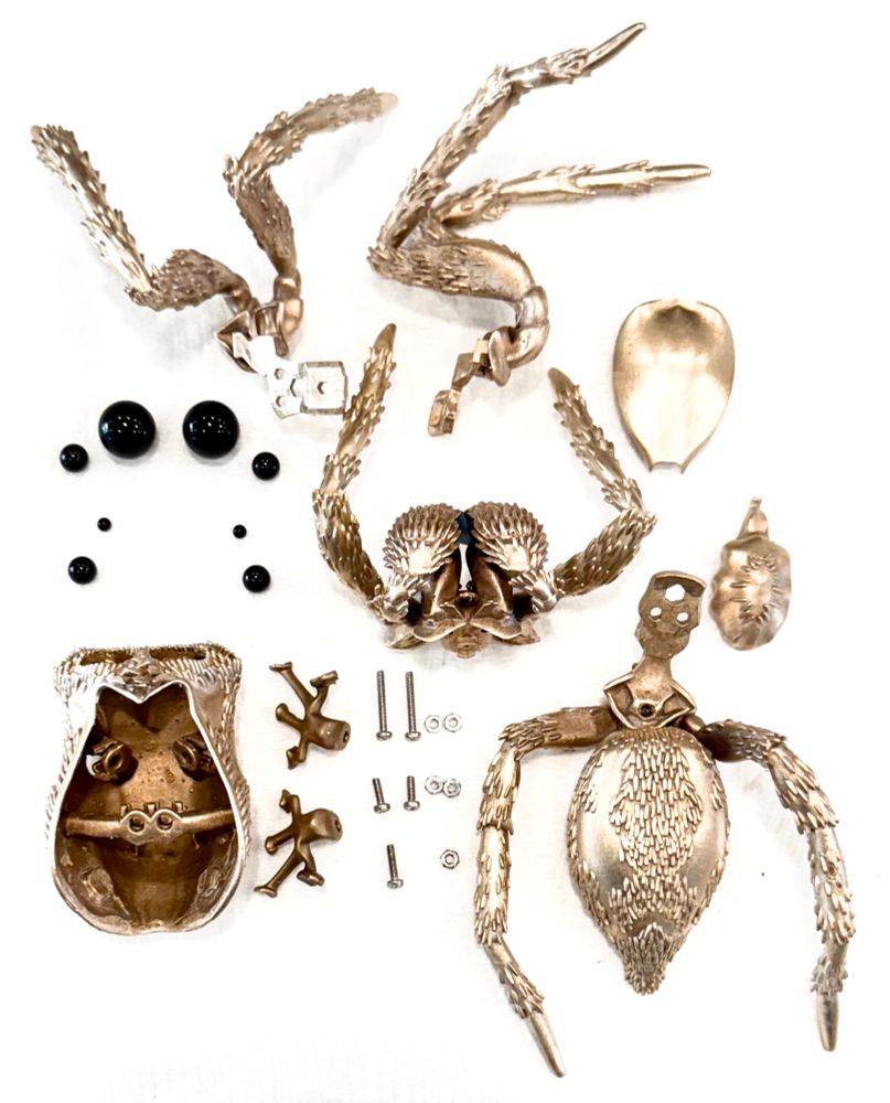An array of bronze parts, black glass balls, and nuts and bolts on a white background 