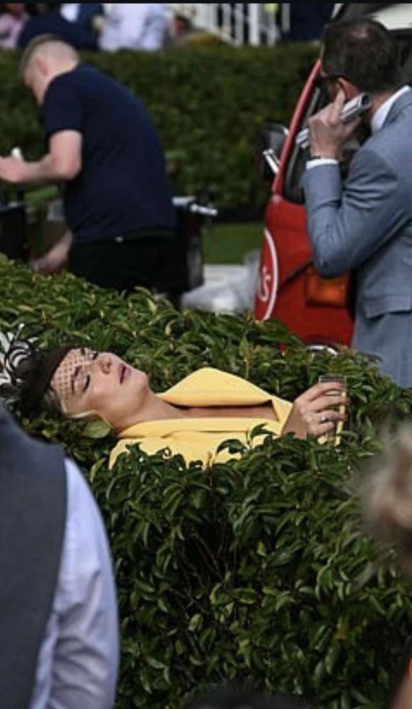 Woman passed out in bush holding glass of champagne 