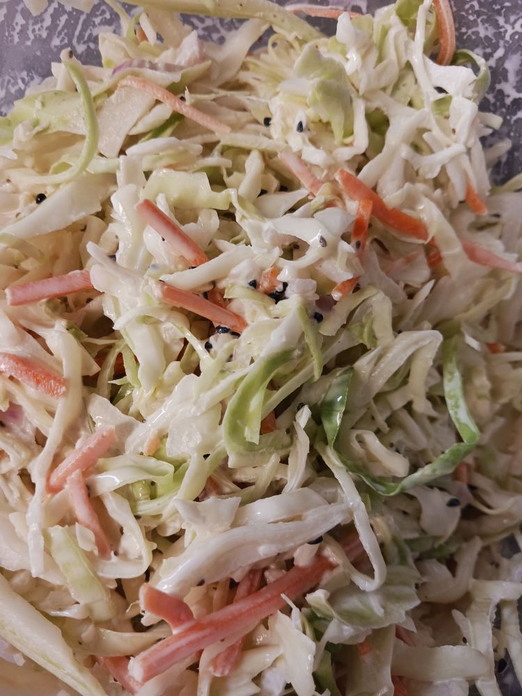 It's Coleslaw! Shredded cabbage and some carrot in a creamy sauce with specks of black spice.