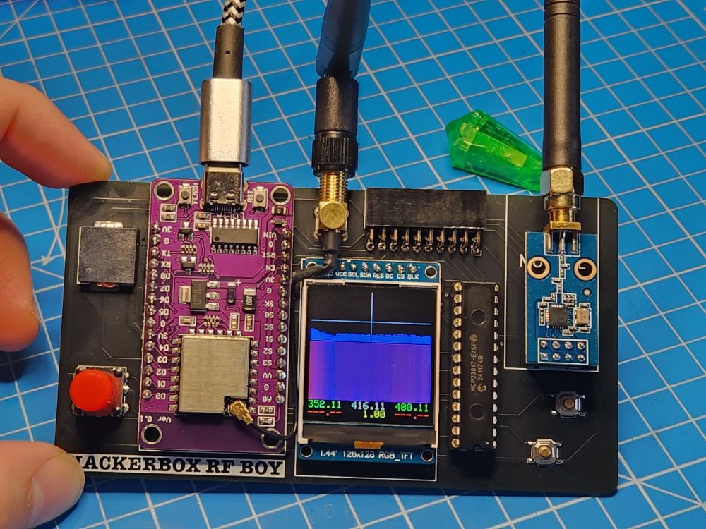 A wide PCB with several daughter PCBs soldered to it; a NodeMCU, a TFT display, and a CC1101 RF module.

The display shows a waterfall graph of little to no activity around the 416MHz band.