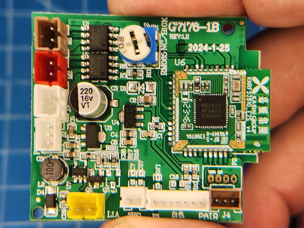 a PCB about 2x2 inches square held between an index finger and thumb. there is a daughter board soldered to it that contains the Bluetooth SoC (system on chip) and antenna. the markings on the chip, 'N52810', identify it as an nRF52810 from Nordic Semiconductor.