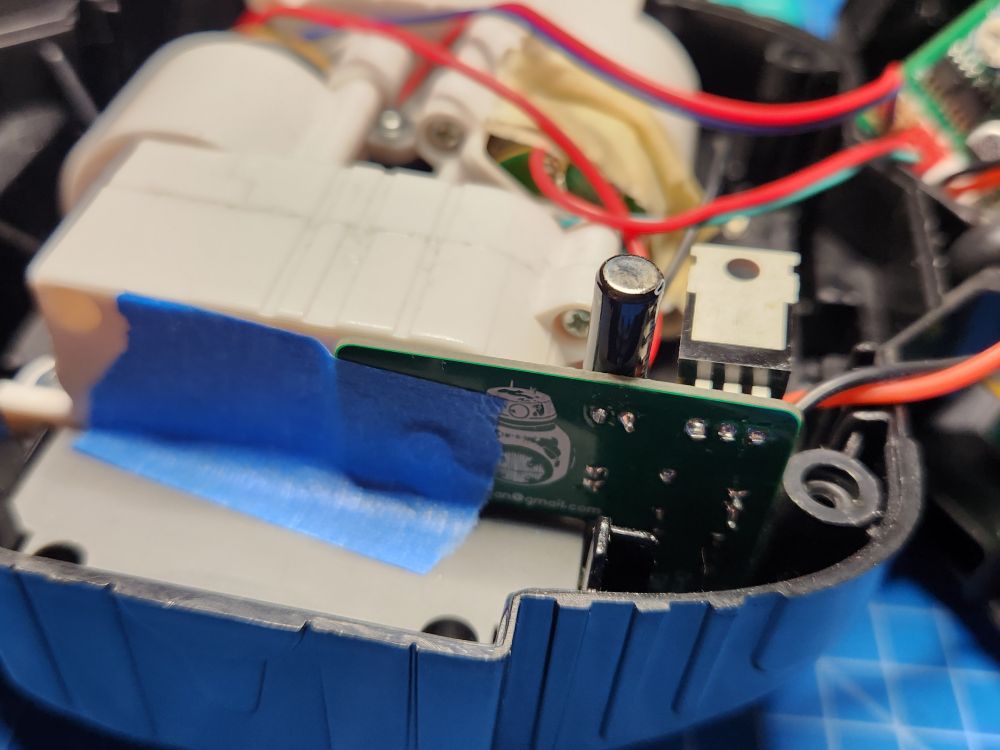 The tilt switch mod PCB is mounted inside a BB droid. Seen from the back, the hole in the PCB has been used to align its location and it's then been taped in place. hot glue works as well.