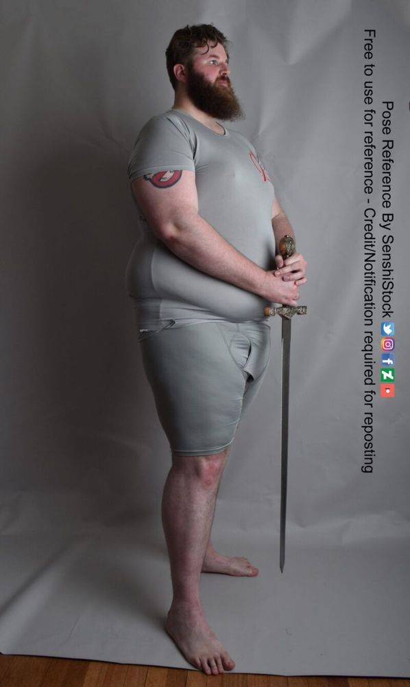 tall fat male model standing in profile with a sword in his hands, tip down by his feet