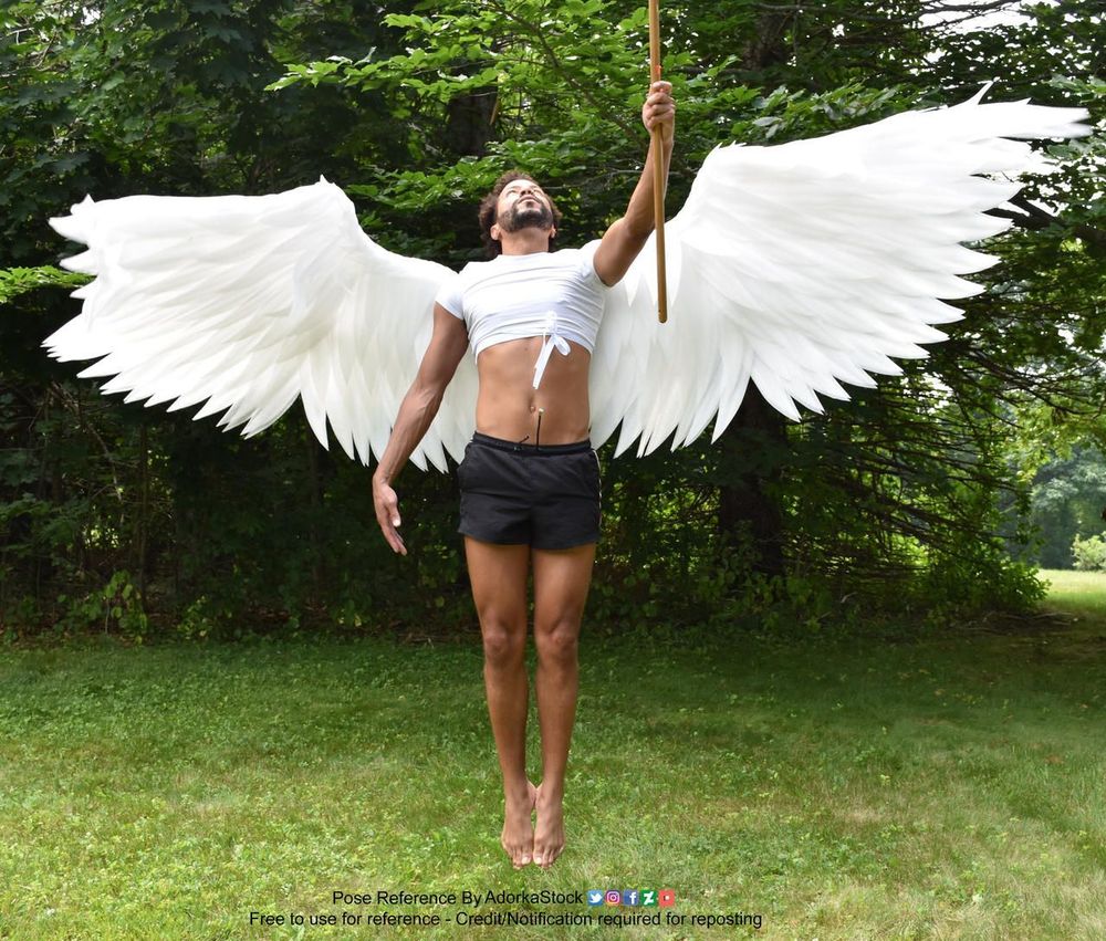 A Latino man jumping in the air with massive white wings attached to his back.