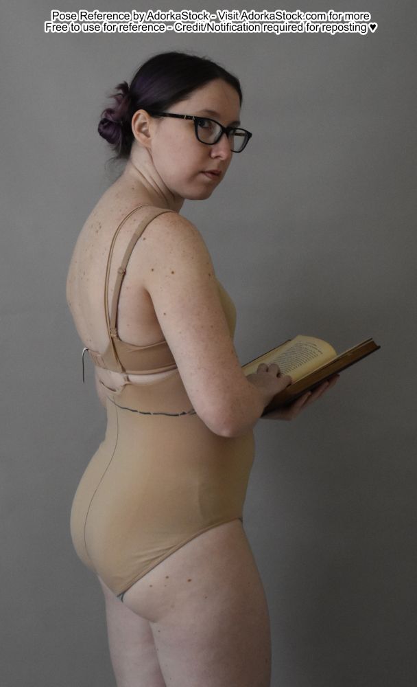 thin white bespectacled female model holding a book facing 3/4 away looking over her shoulder at you 
