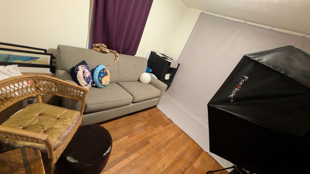 More or less clean studio with a chair, a couch and a backdrop and a big light