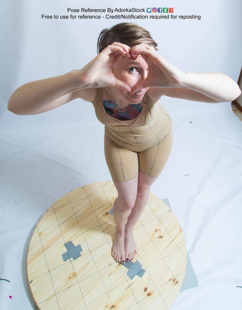 White woman standing making a heart shape with her fingers and looking through the shape with one eye.