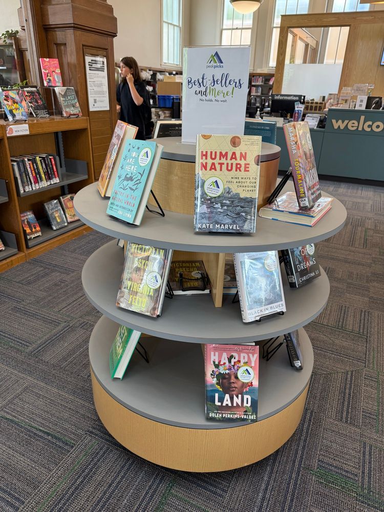 A stand at a library with books displayed including “Human Nature”. 