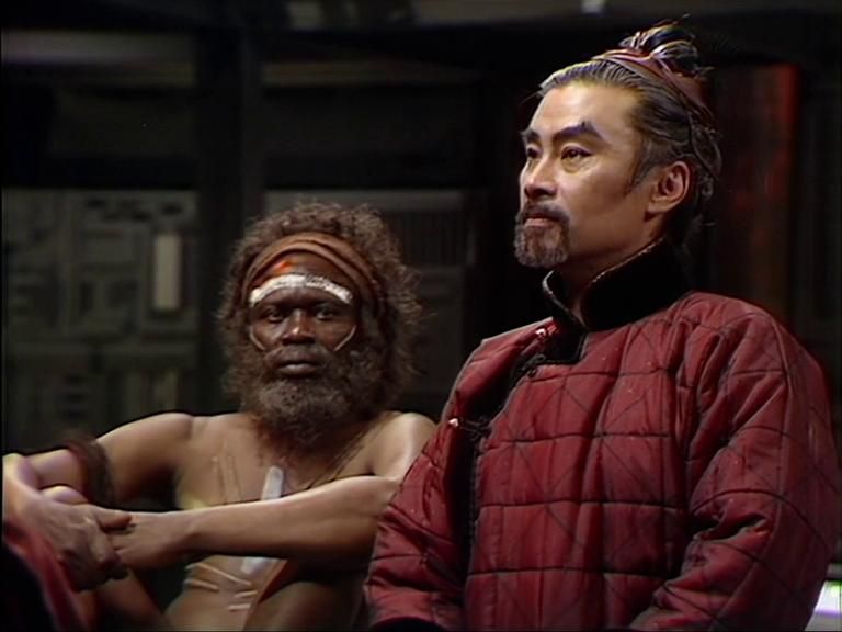 Ilario Bisi-Pedro as Kurkutji, an Indigenous Australian, and Burt Kwouk as Lin Futu, a Chinese mandarin, in Four to Doomsday (1982).