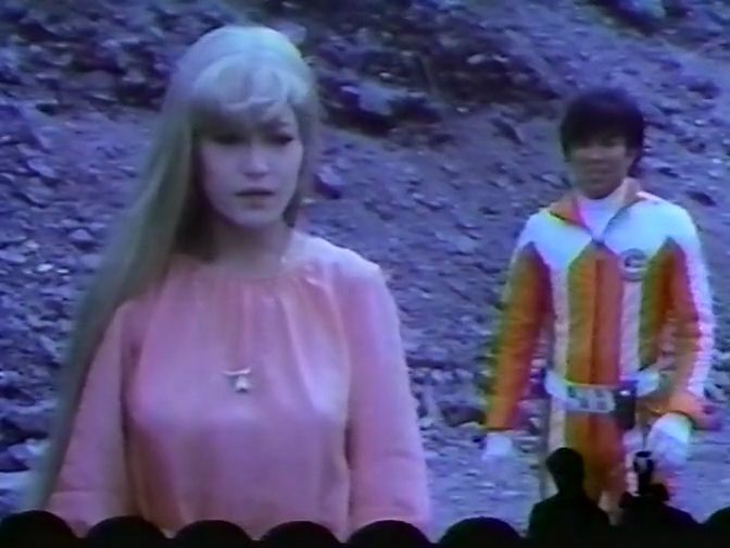 Rita (with long blonde hair) and Ken (no longer in a wig-helmet) stand on a pile of, I dunno, rubble or something. A perfect setting for them to work out their romantic difficulties.