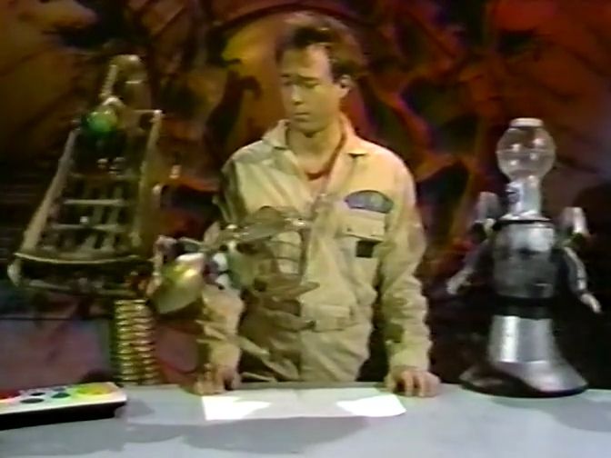 On the Satellite of Love, GPC and Tom have disassembled Crow for a prank. (GPC is carrying Crow's neck and head in her mouth.) Joel isn't amused, but honestly neither are the bots. Oh well, some pranks are like that.