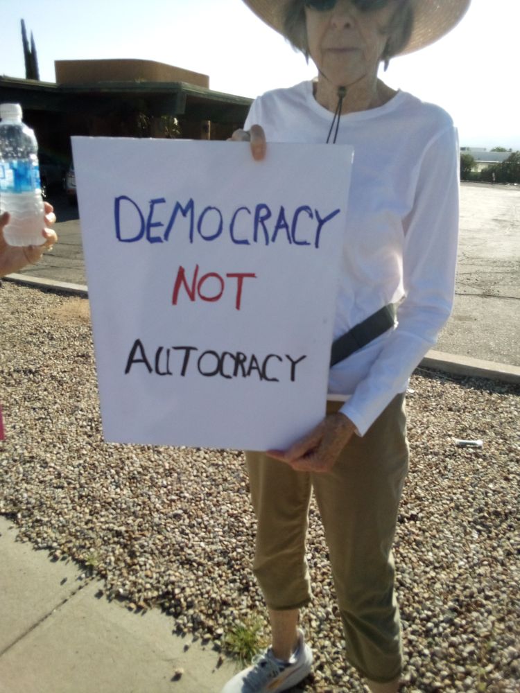 Protester holding a sign in Green Valley, AZ that reads: "Democracy, Not Autocracy"