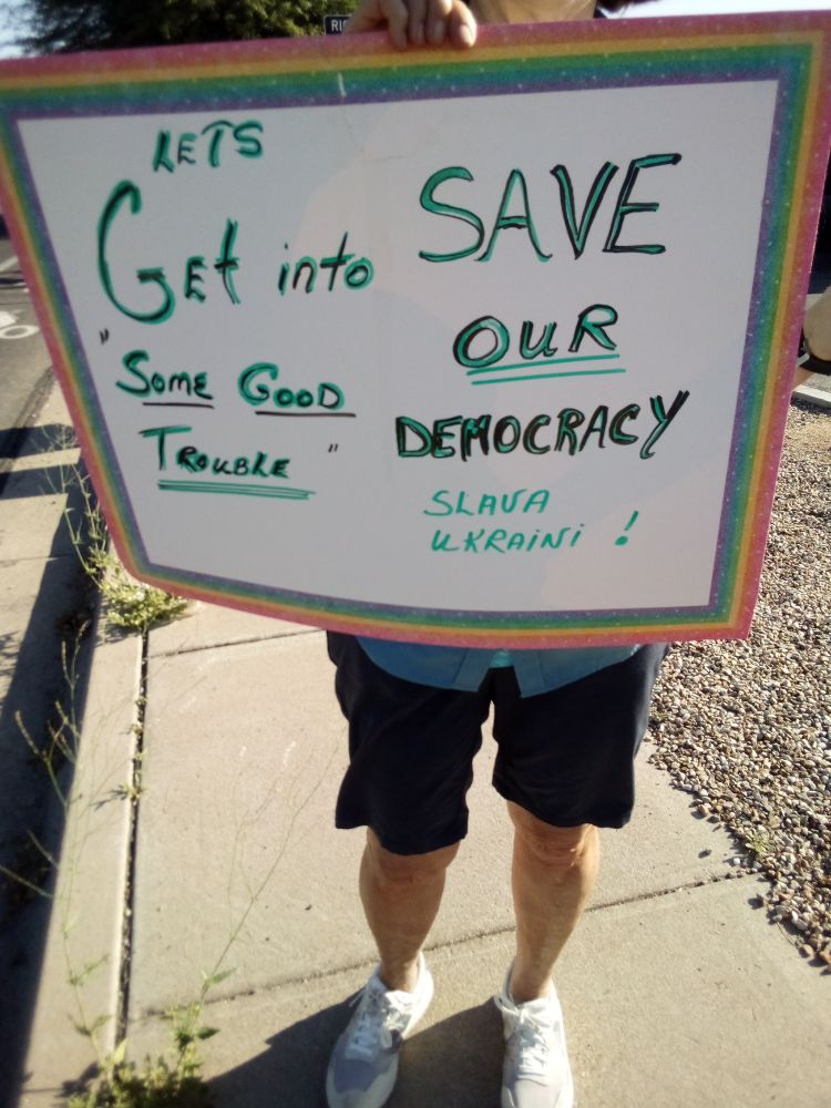 Protester holding a sign in Green Valley, AZ. Sign reads "Let's Get into Some Good Trouble: Save Our Democracy, Slava Ukraine"