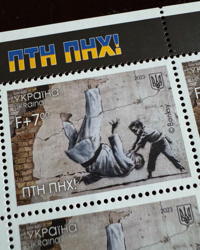 Postage stamp from Ukraine, featuring the artwork of Banksy, a child, flipping an image of Putin on his back in a judo move with the text fuck Putin in Ukrainian