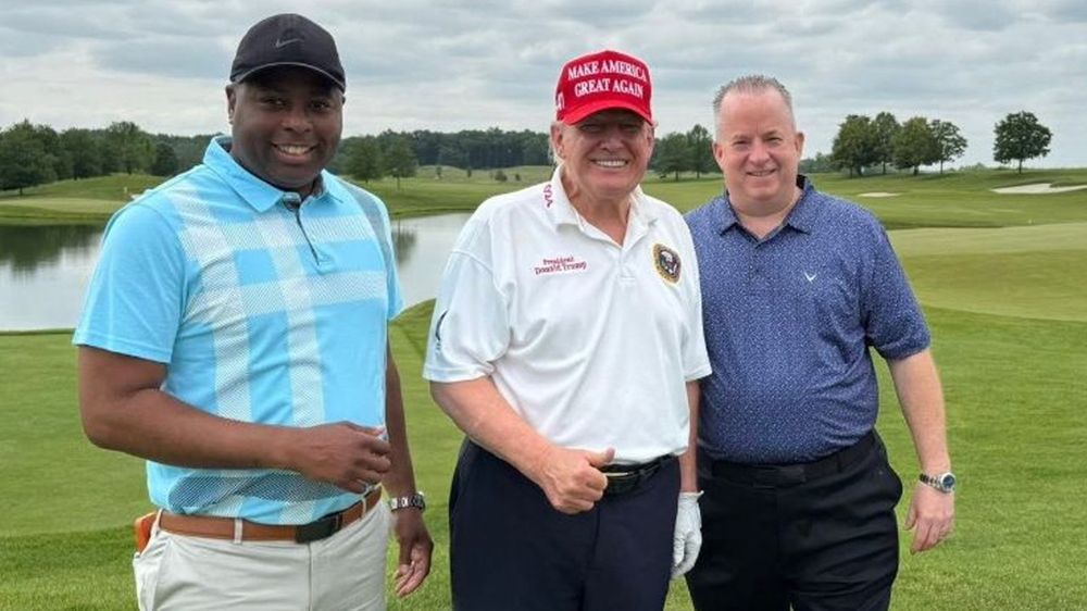 kaz daughtry and john chell posing with donald trump on a golf course
