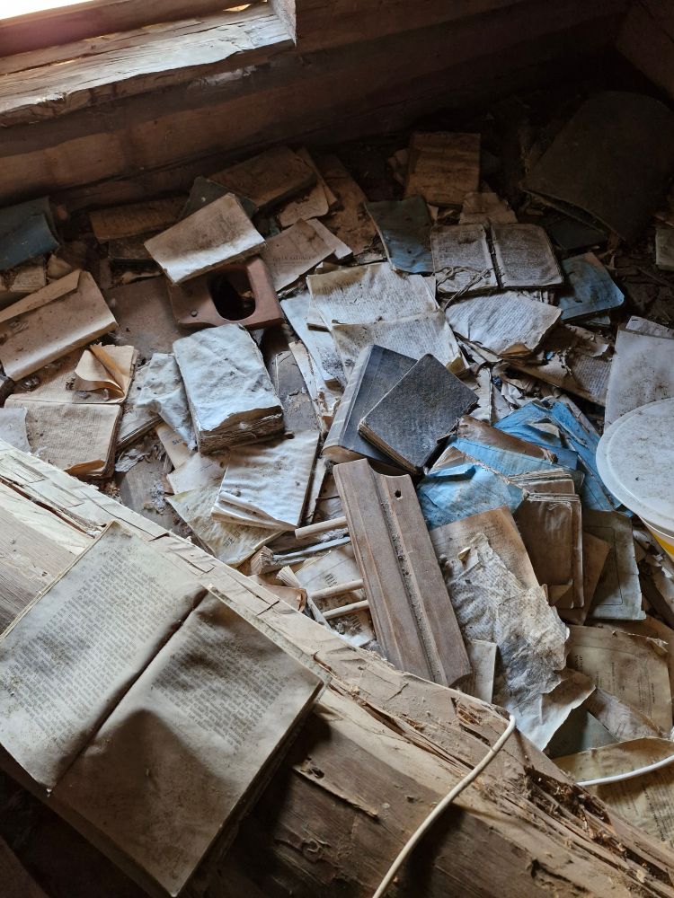 A disorganised pile of decaying books in an attic.