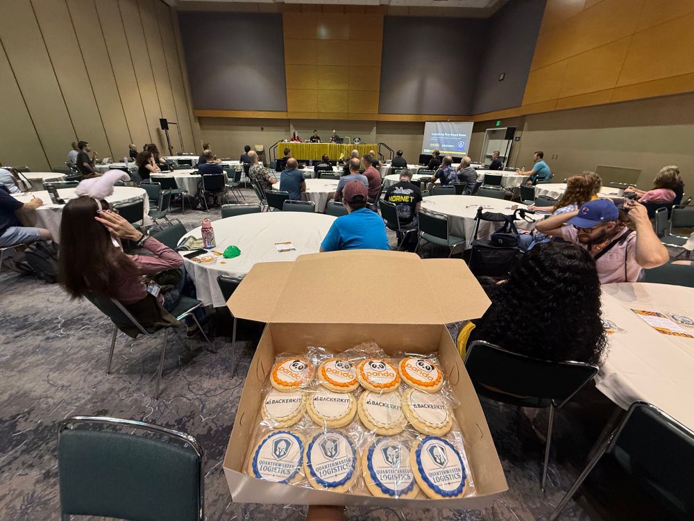 Cookies with the logos of Panda, BackerKit, and QML with the presentation audience in the background.