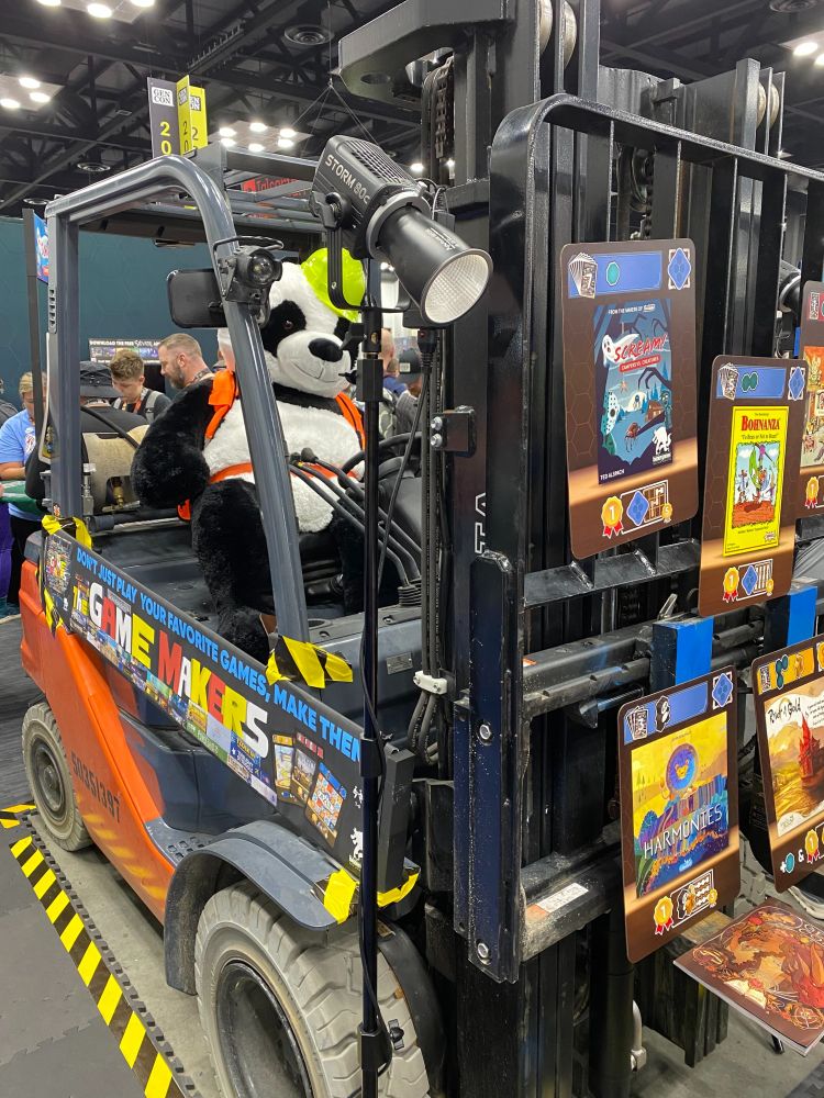 A folklift display for the board game Game Makers - with a giant plush panda in the driver's seat.