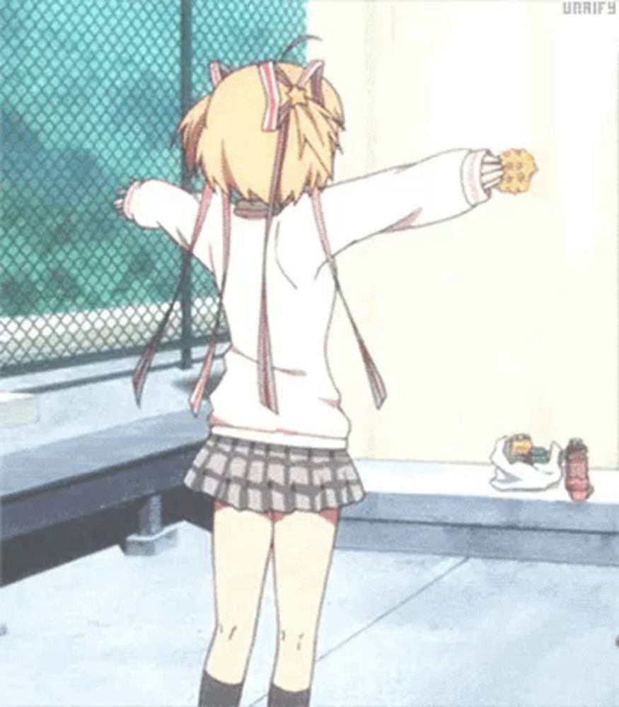 a girl in a skirt is holding a cookie with her arms outstretched in front of a fence .