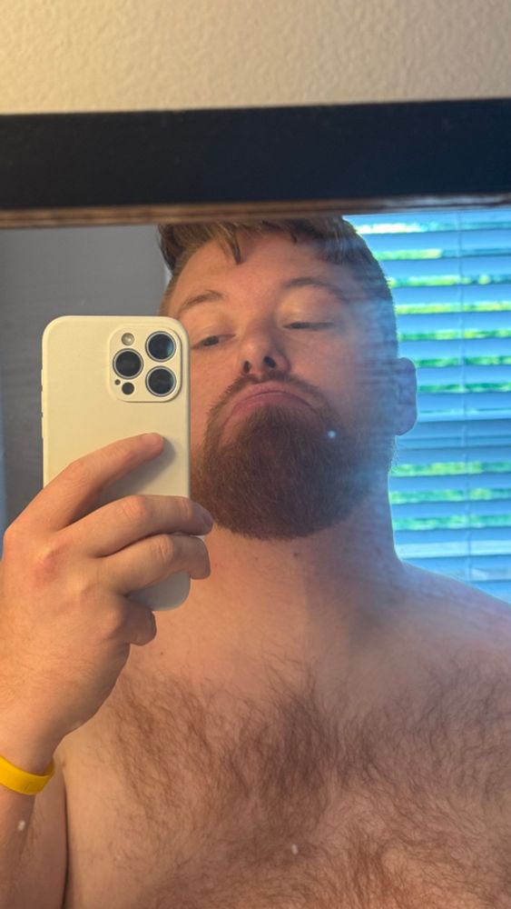 Ginger taking a selfie holding an iPhone with a trimmed beard.