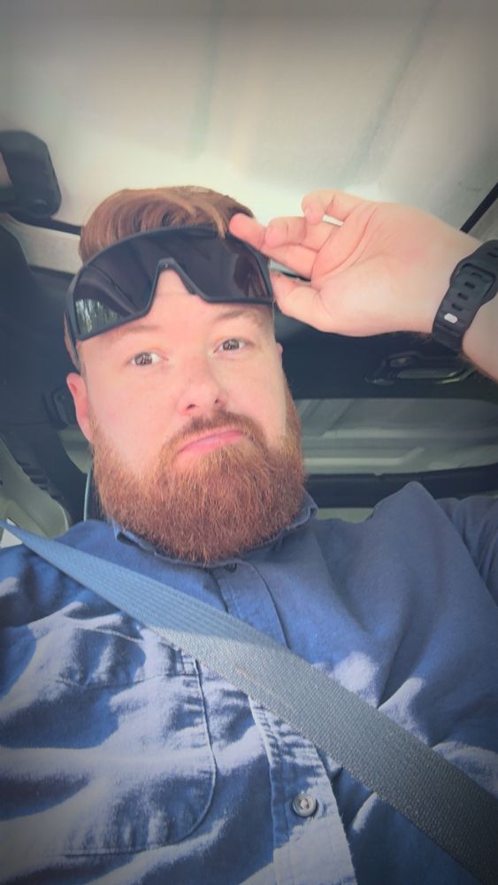 Ginger with a beard wearing his seatbelt and douche sunglasses