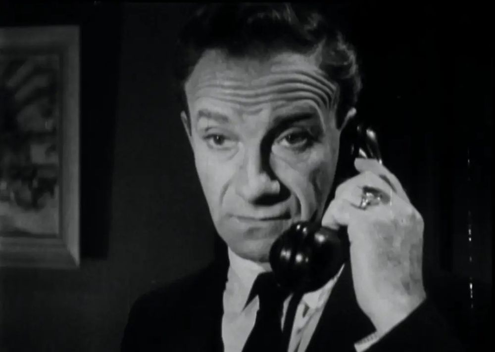 Jonathan Harris holding a phone to his head. 