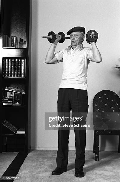 Older Don Knotts lifting weights in casual wear 