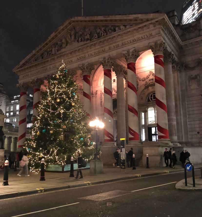 A large christmas tree in front of a historical building in Bank