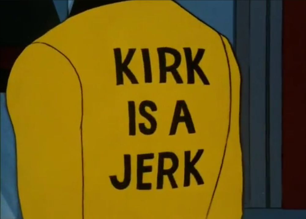 Screenshot from Star Trek: The Animated Series episode "The Practical Joker" 

We can see Captain Kirk's back turned to the camera, on it in very legible, large black lettering it plainly says "KIRK IS A JERK"