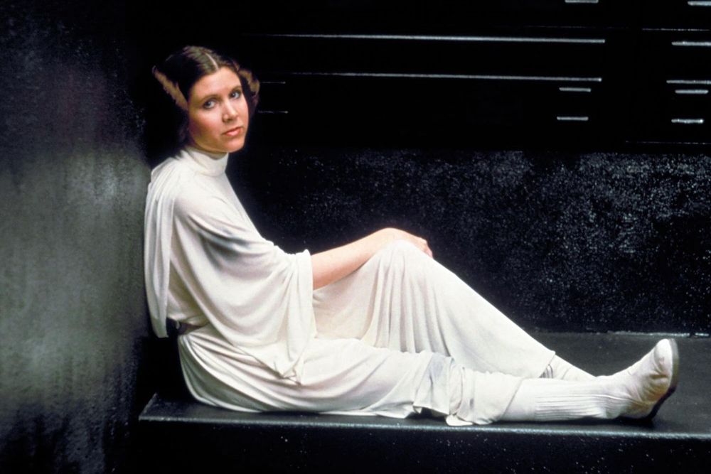 Princess Leia sitting in her cell in Star Wars A New Hope wearing her signature white dress and brown hair in bunz