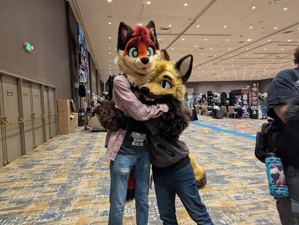 Two fox partial fursuiters hugging