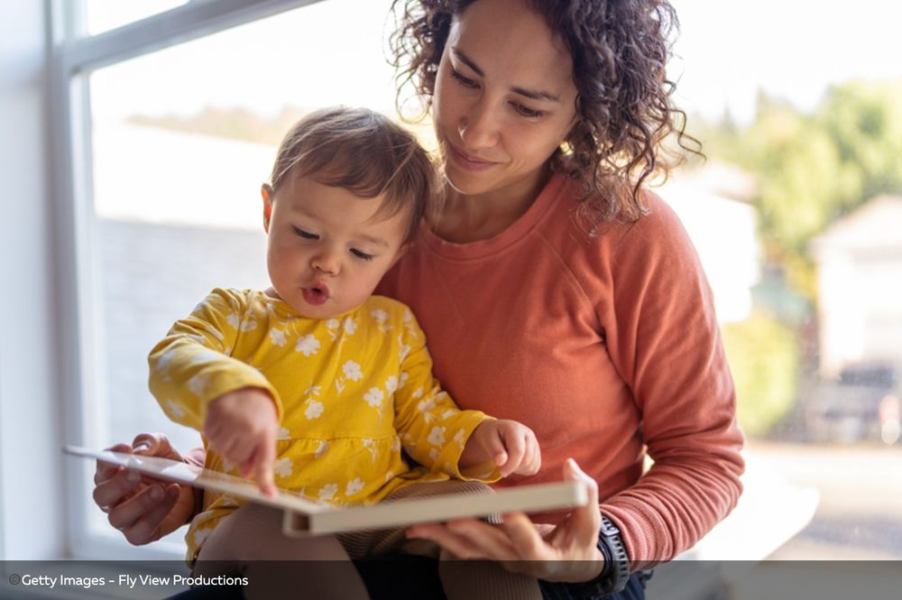 Mom with toddler reading a book together.