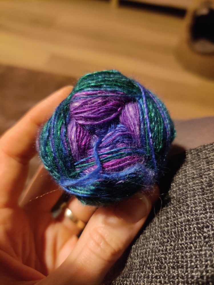 Een bolletje wol met kleurverloop van paars naar blauw naar groen