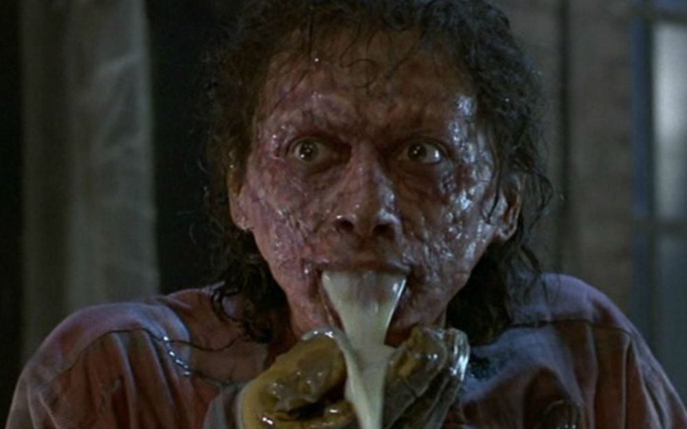 Scene from The Fly with Jeff Goldblum's character in the process of transforming into a fly, vomiting fluid to predigest his food.