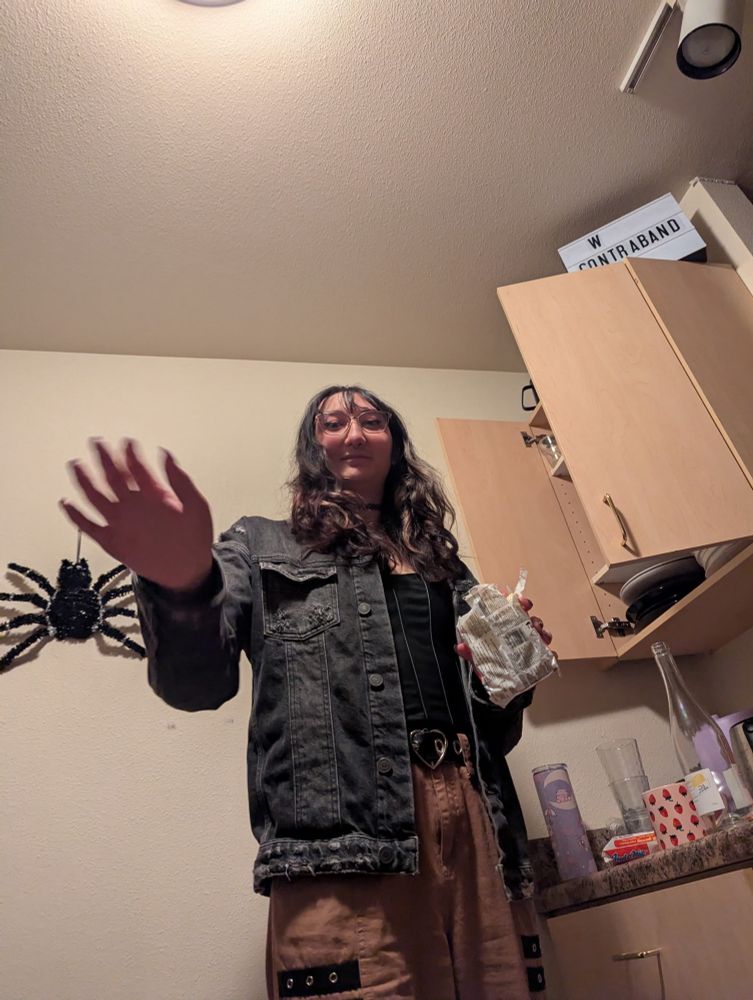 Maia holding a pack of ramen waving downward at her roommate